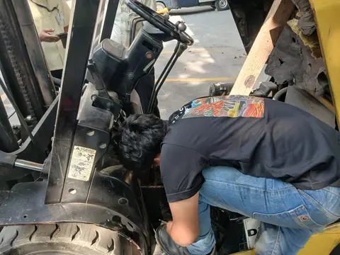 Pemeriksaan sistem kemudi forklift saat service on-site di halaman gudang