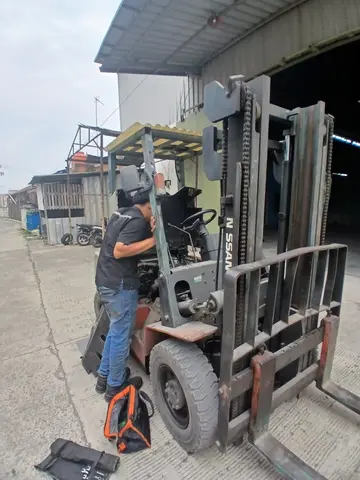 Teknisi memeriksa mesin forklift Nissan saat perbaikan on-site