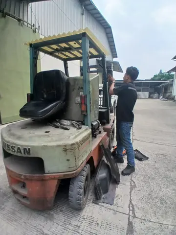 Teknisi melakukan service forklift Nissan on-site di halaman pabrik